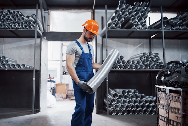 Portrait of a young worker in a hard hat at a large metalworking plant.