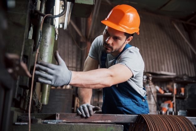 Portrait of a young worker in a hard hat at a large waste recycling factory.