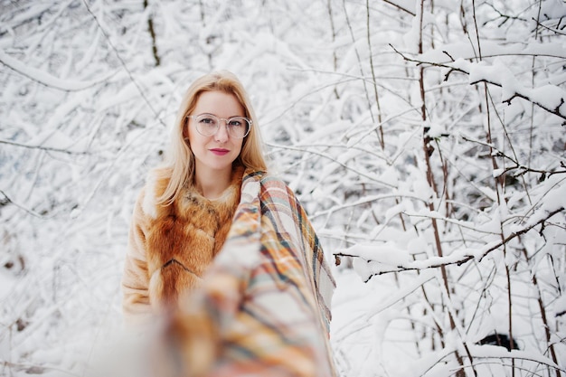 Free photo portraiy of blonde girl in glasses red fur coat and scarf at winter day