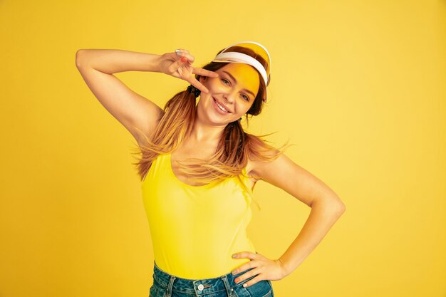 Posing cute, smiling. Caucasian woman's portrait on yellow studio background.