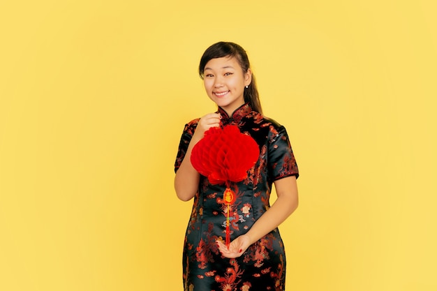 Free Photo posing with lantern, smiling, inviting. happy chinese new year. asian young girl portrait on yellow background. copyspace.