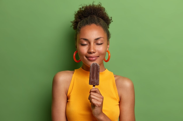 Positive African American woman chills with cold ice cream isolated