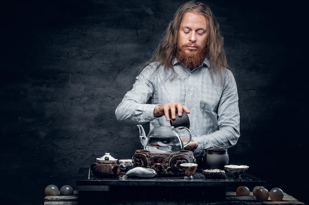 Free Photo positive bearded male pours hot water in a tea ceremony.