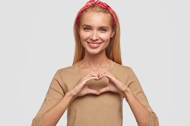 Free Photo positive blonde young woman posing against the white wall