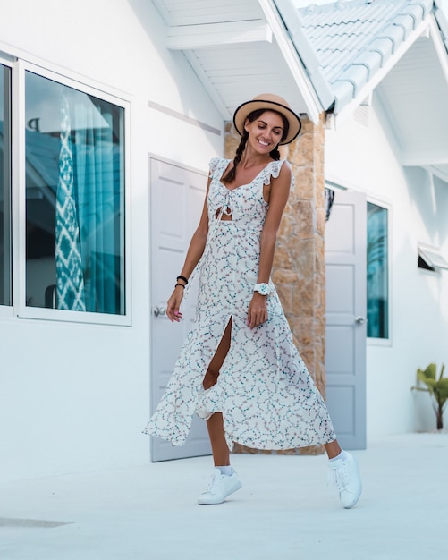 Positive calm woman in light summer dress, straw hat, tropical location