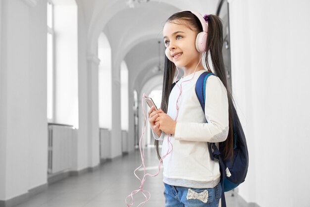 Positive and clever school girl istening music