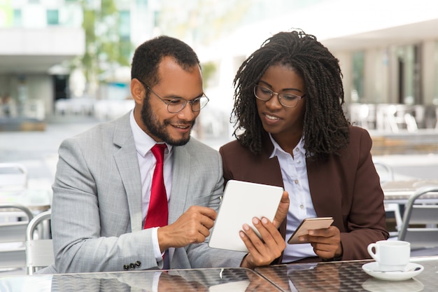 Positive colleagues comparing data on their gadgets