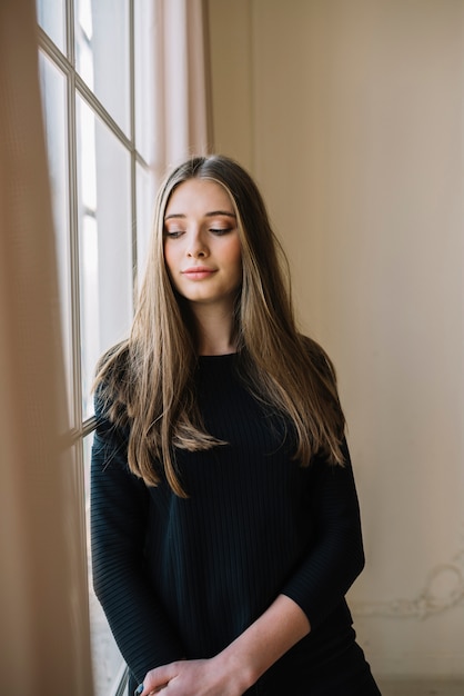 Positive elegant young woman in black wear in room