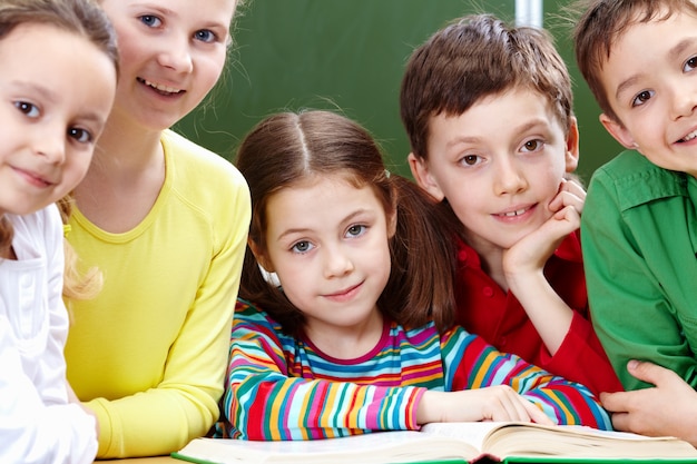 Free photo positive elementary students reading a book in class