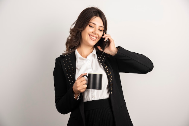 Positive employee talking on telephone while holding tea