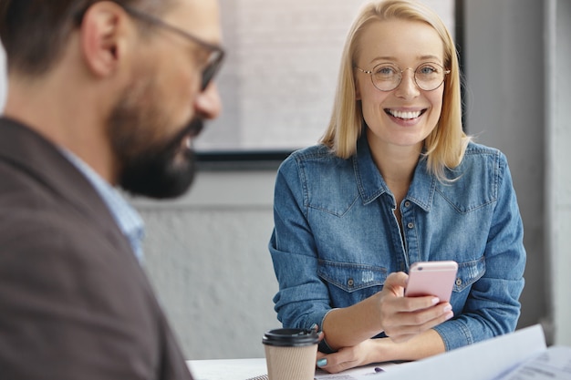 Positive female assistant and bearded serious male entrepreneur in office