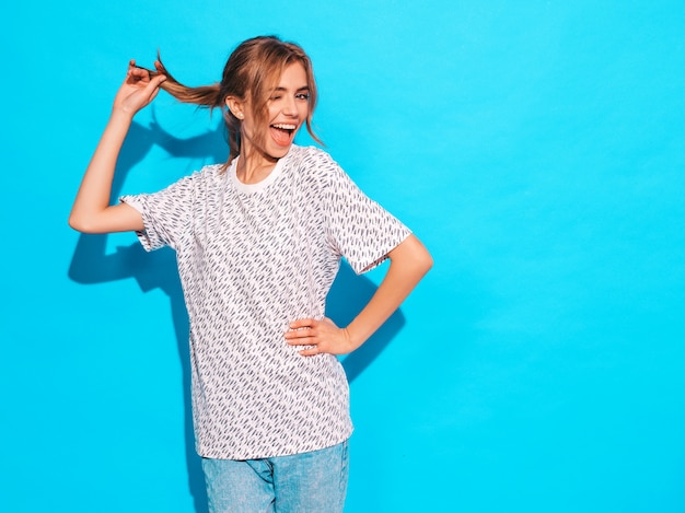 Free Photo positive female smiling. funny model posing near blue wall in studio.winks