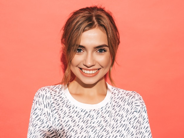 Positive female smiling. Funny model posing near pink wall in studio