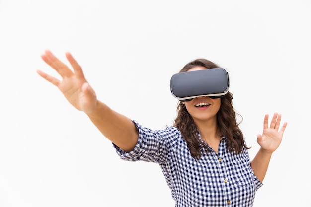 Positive female user in VR goggles touching air and smiling