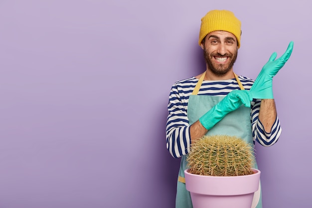 Positive gardener wears rubber gloves, ready for transplanting cactus in new pot