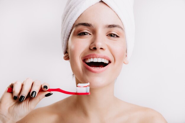 Positive healthy girl does morning treatments for beauty and hygiene. Woman with white towel on her head posing with toothbrush.