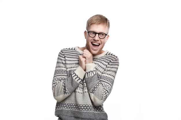 Free Photo positive human emotions, feelings, reaction and attitude. picture of funny ecstatic male student in glasses, holding clenched fists on his chest and smiling broadly, excited with results of exams