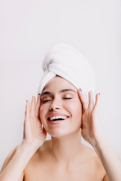 Positive lady enjoys morning spa treatment. Girl after shower posing on isolated wall.