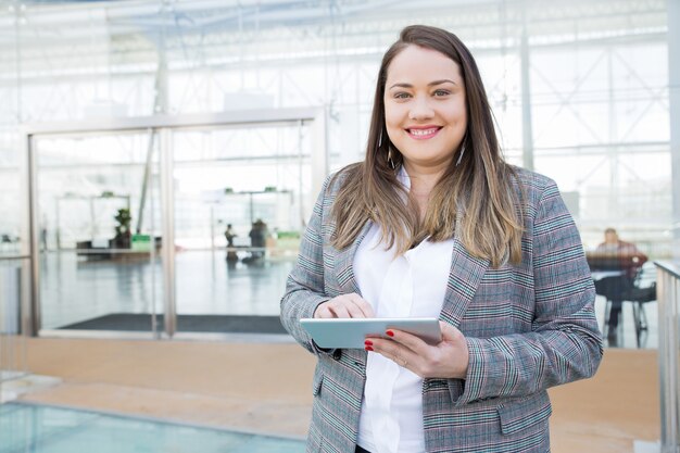 Positive lady with tablet posing in business center