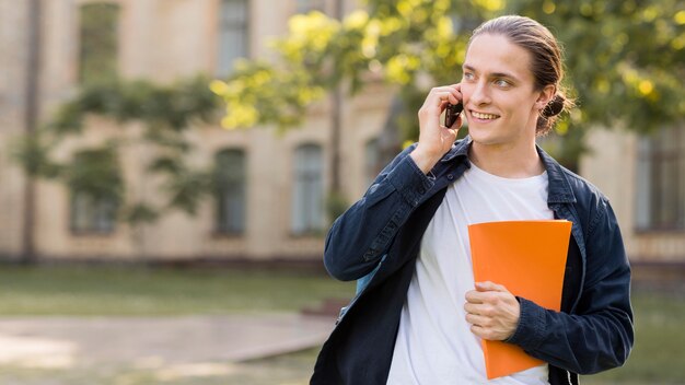 Positive male student talking on the phone