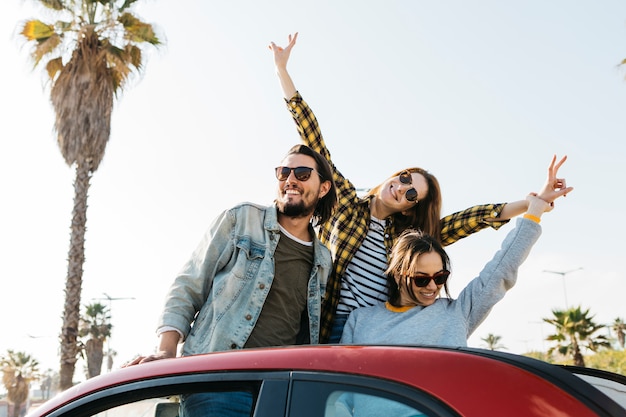 Positive man and smiling women having fun and leaning out from auto