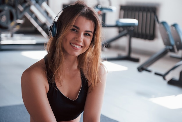 In positive mood with great music. Photo of gorgeous blonde woman in the gym at her weekend time