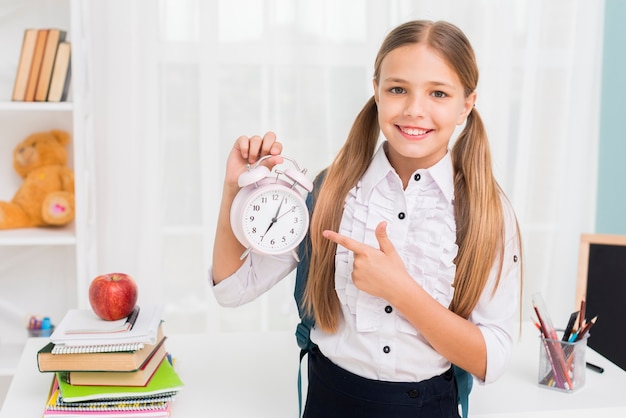 Free photo positive schoolgirl pointing at clock