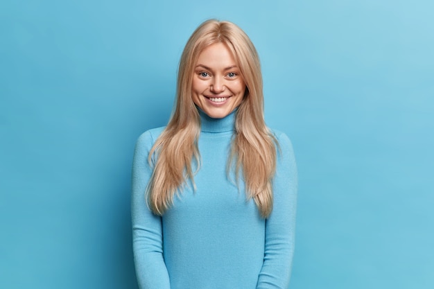 Free photo positive shy woman with pleasant smile looks happy, dressed in casual turtleneck