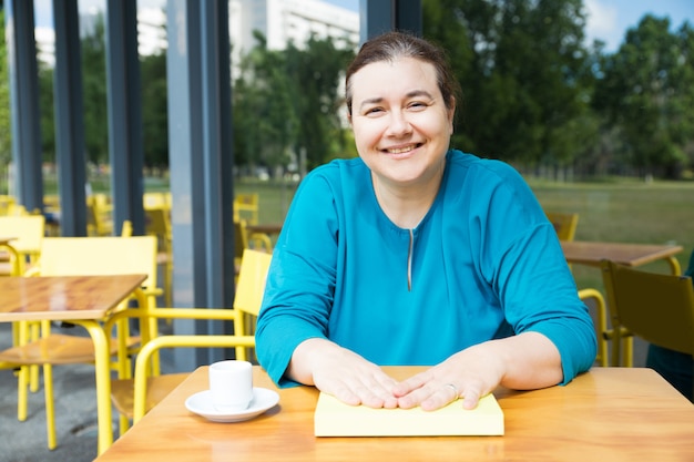 Free photo positive teacher drinking coffee at college cafe