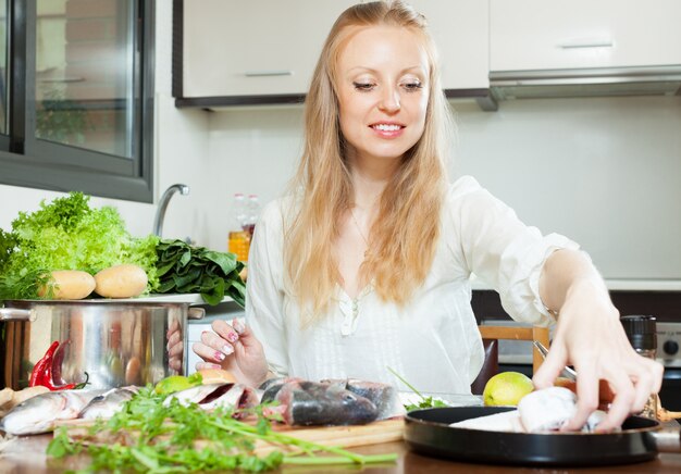 Positive woman cooking fish in flour