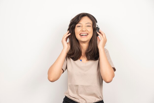 Positive woman listens music in headphones and enjoys nice sound.