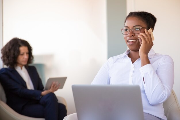 Positive young female manager talking on phone