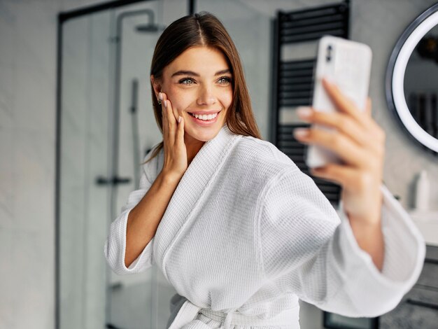 Positive young woman in a bathrobe taking a selfie