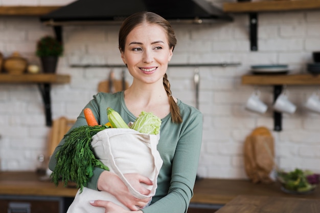 Free photo positive young woman holding bag with organic vegetables