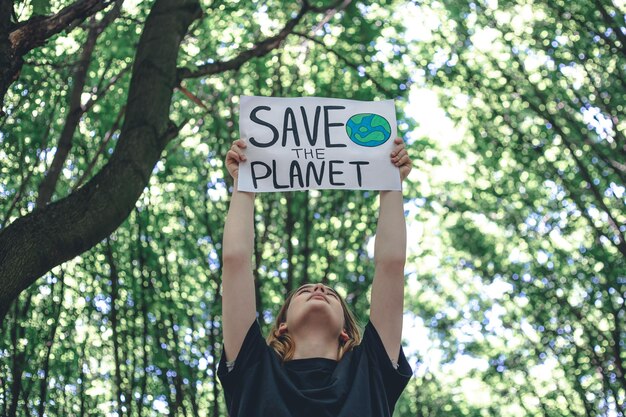 Poster in the call to save the planet in female hands in the forest