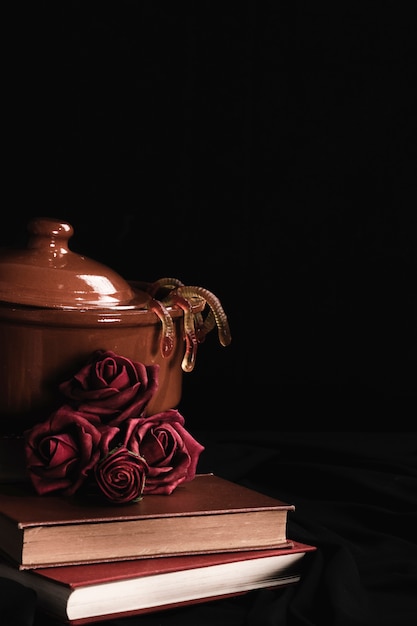 Pot with roses and jelly on black background