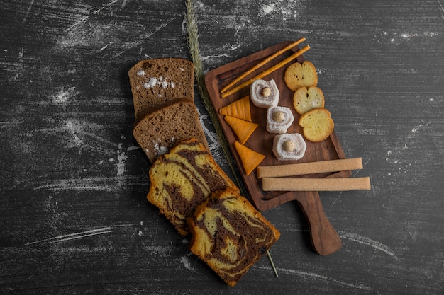 Free Photo potato chips with pastry products on a wooden platter and bread slices aside