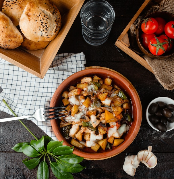 Potato fried in a pottery and a glass of water