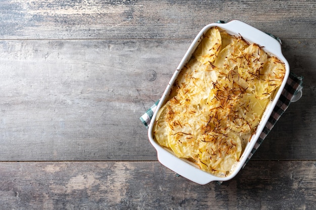 Potato gratin baked with cream and cheese on wooden table Close up