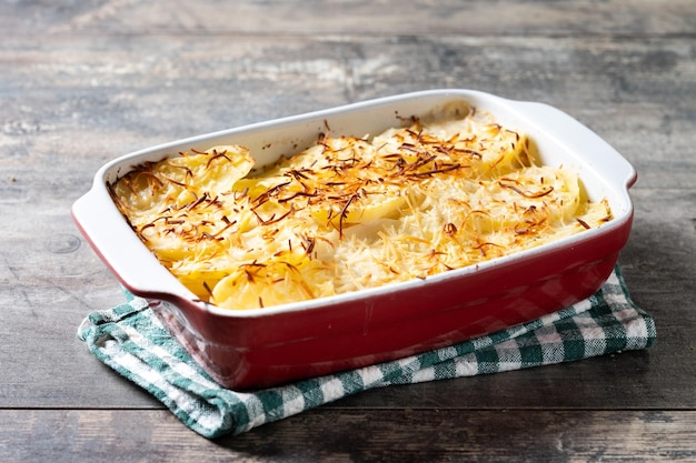 Potato gratin baked with cream and cheese on wooden table