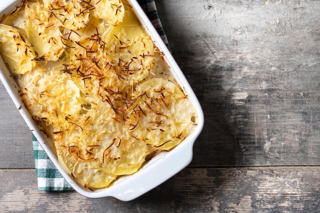 Potato gratin baked with cream and cheese on wooden table