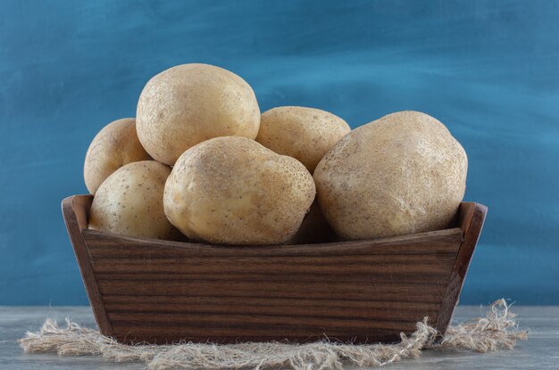 Potatoes in the box, on the towel , on the marble table. 