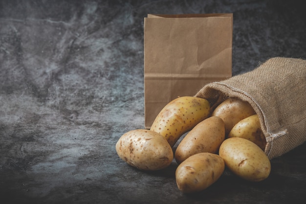 Potatoes pour out of sacks on gray floor