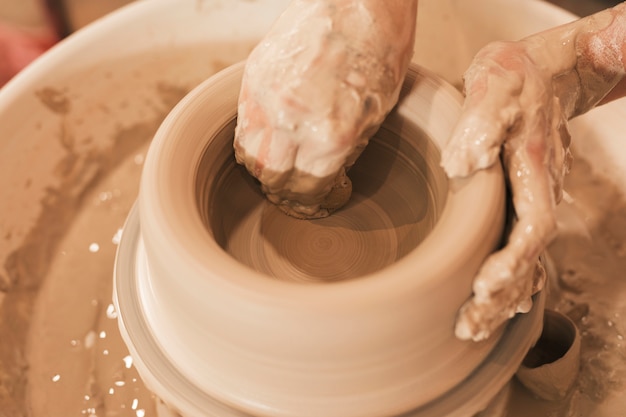 Free photo a potter's hands shaping clay on a wheel