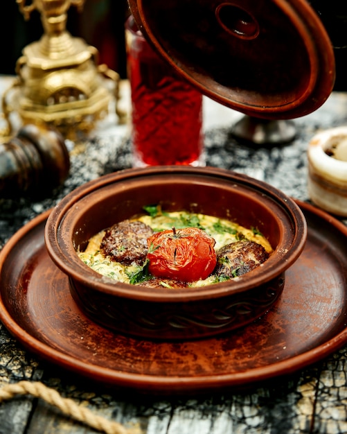 Free Photo a pottery pan with meat balls cooked in egg with spinach topped with tomato