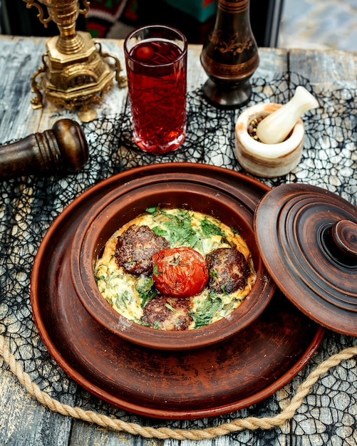 Free photo a pottery pan with meat balls cooked in egg with spinach