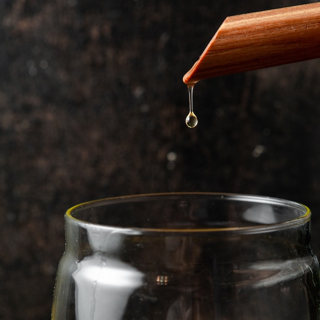 Free photo pouring oil into glass jar close-up