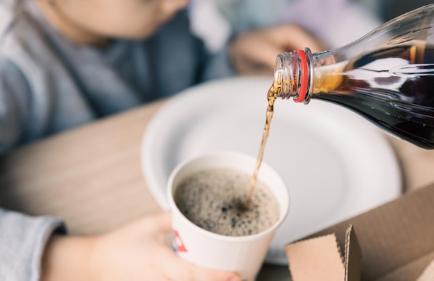 Pouring soda drink from bottle to glass close up