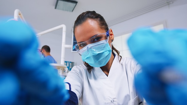 Free photo pov of patient in a dental clinic sitting on surgery chair while professional dentist working with gloves during examination in modern clinic using sterilized instruments