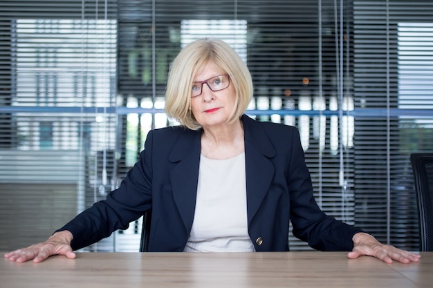 Free Photo powerful senior lady boss sitting at desk